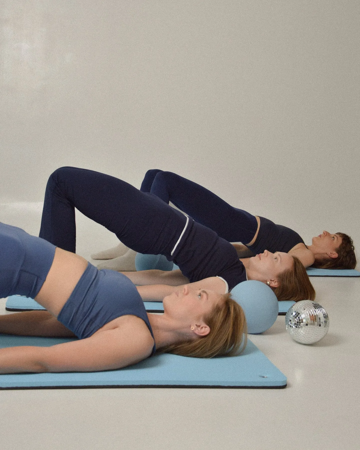 Grupa ćwiczy mostek na matach podczas zajęć pilates