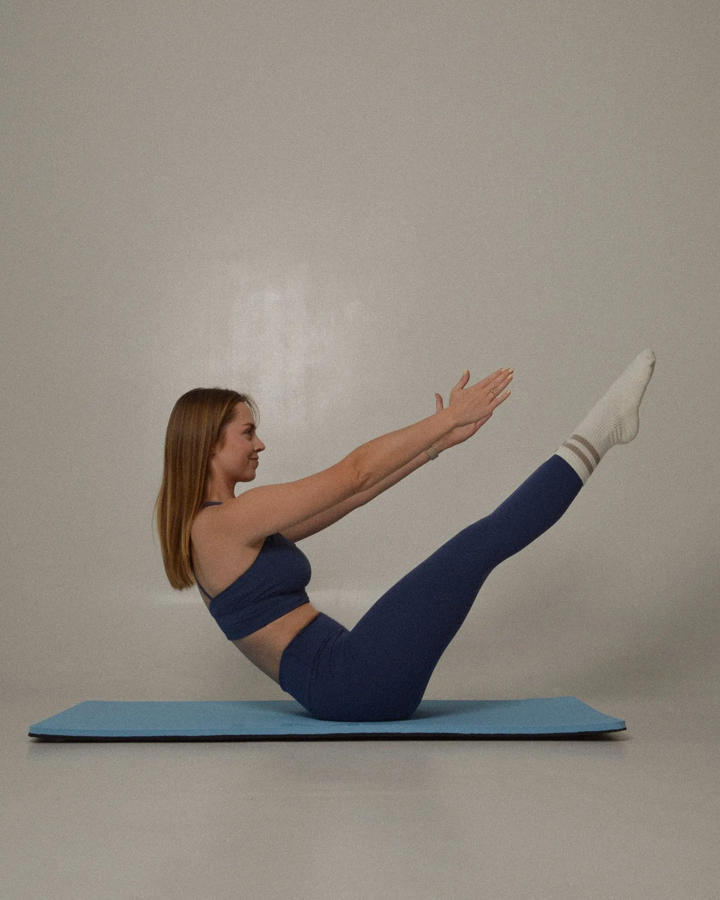 Kobieta ćwiczy pilates w pozycji teaser na macie